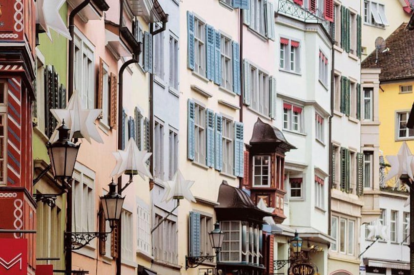 A row of colorful buildings with shutters, a street lamp, and a small tower-like structure. 3