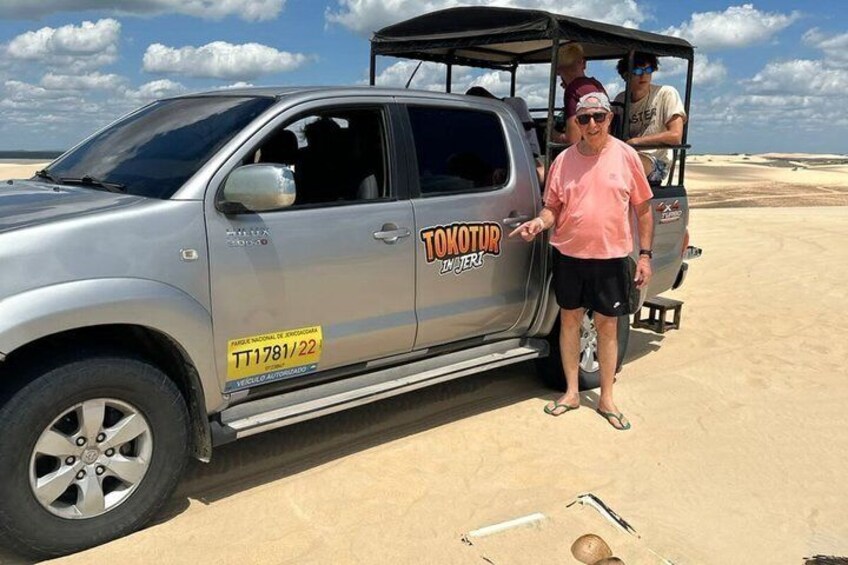 En silverfärgad SUV med "TOYOTUR"-loggan på, parkerad på en sandstrand. 2