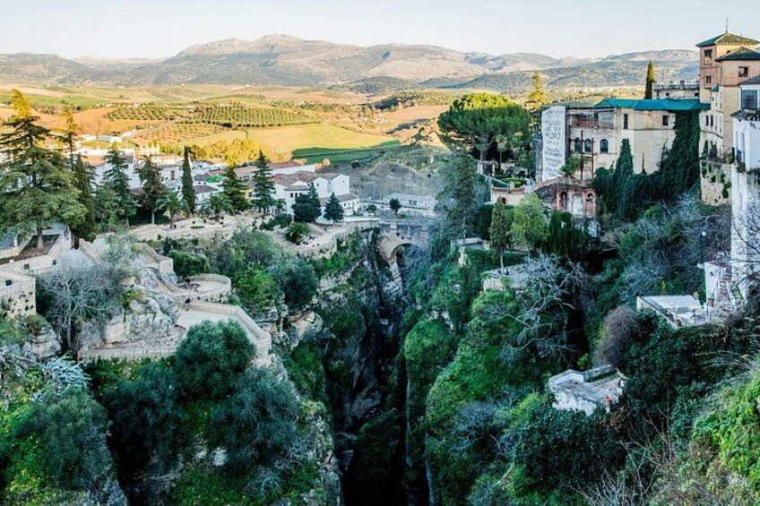 A mountainous village with traditional architecture, dense greenery, and distant hills. 1