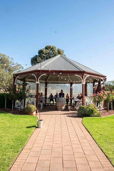 A gazebo with a tiled walkway leading to it, surrounded by grass and trees. 5