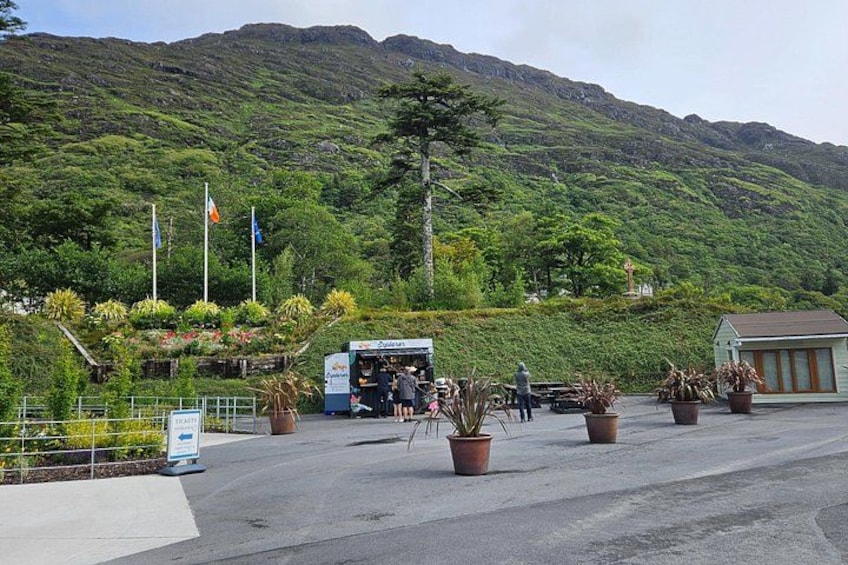 A parking area with potted plants, a bus, and a mountainous backdrop. 2