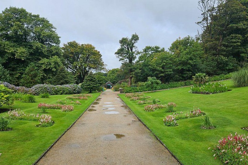 A garden pathway with a central path flanked by neatly trimmed grass and flower beds. 4