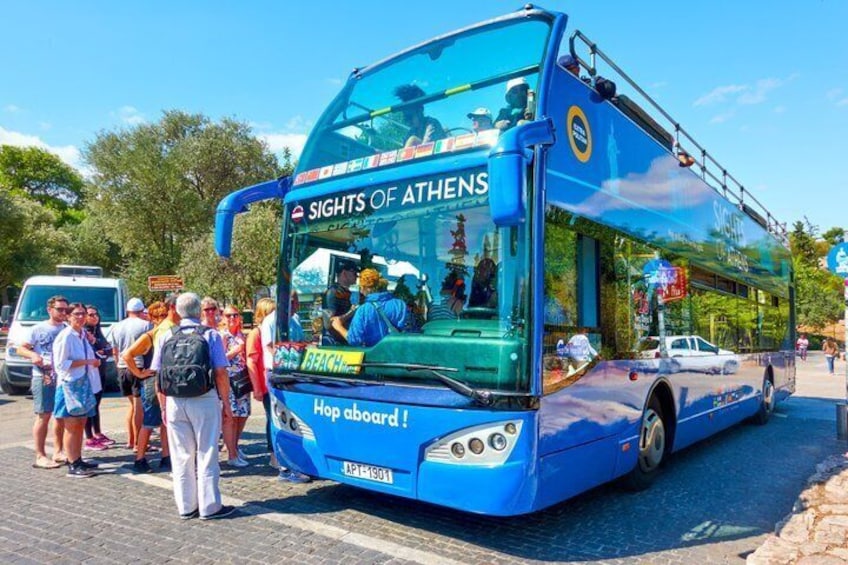 A blue double-decker bus with 'Sights of Athens' written on the front, parked on a street with people around it. 2