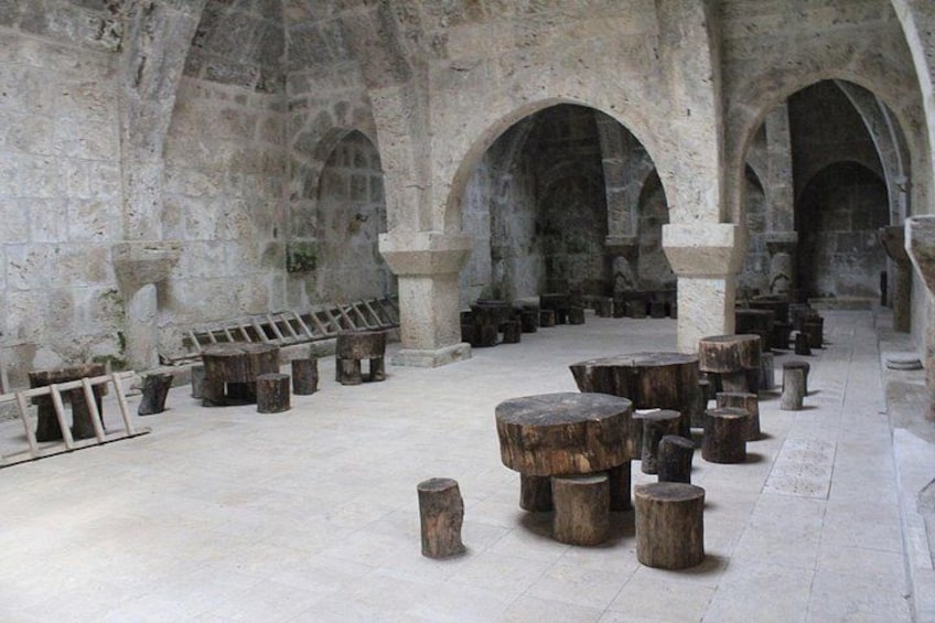 Un antiguo salón de piedra con techos abovedados y bancos de madera. 3