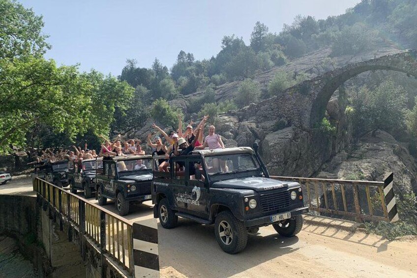 Un convoy de jeeps cruzando un puente, con pasajeros levantando las manos. 1