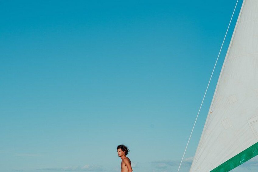 A person standing on a boat with a clear blue sky in the background. 2
