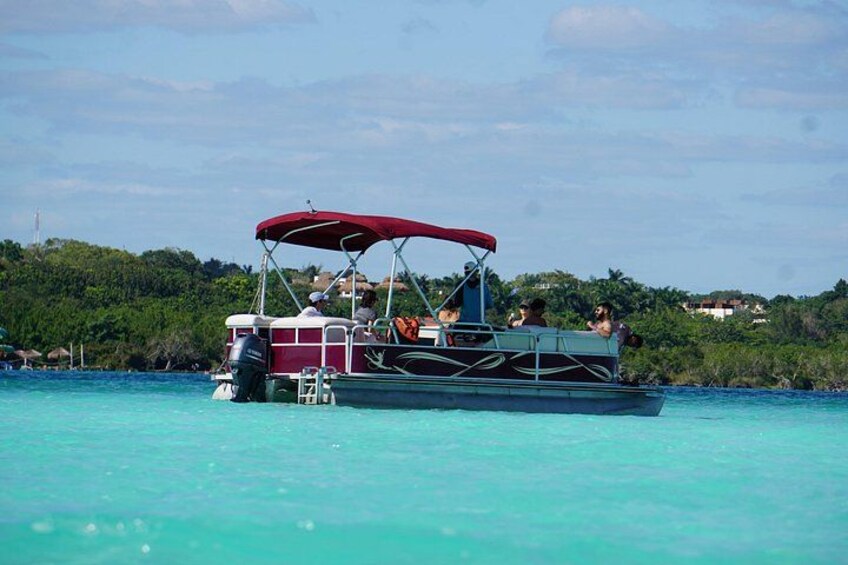 A boat with a red canopy on turquoise water, surrounded by greenery and houses in the background. 4