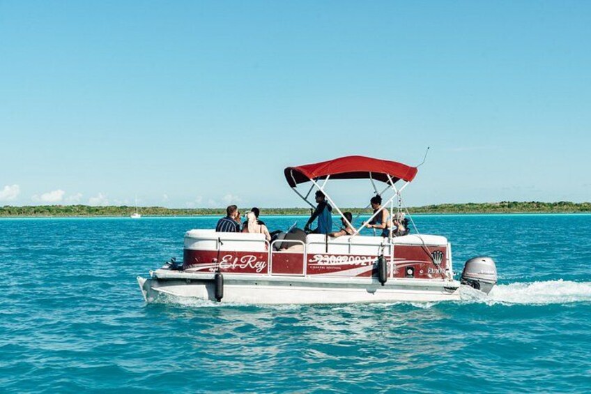 A boat with a red canopy, people on board, and calm blue water. 2