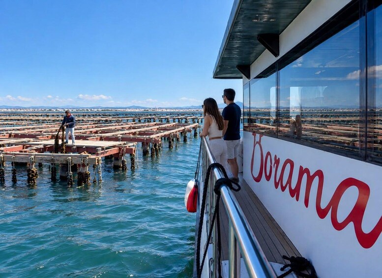 A boat with the name 'Borama' docked at a pier with a person working on the dock and another person standing on the boat. 1