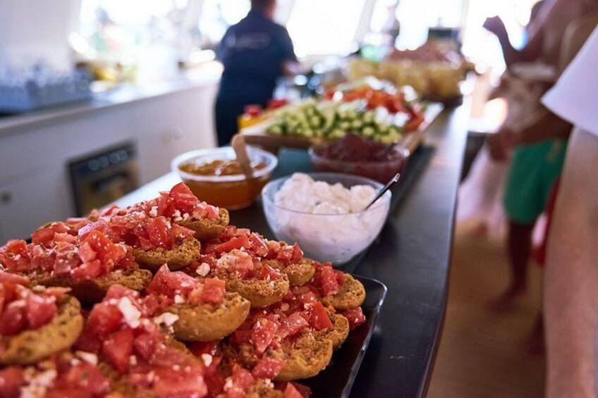 Une table de buffet proposant divers plats, notamment un plat contenant des tomates coupées en dés et un bol de crème blanche. 3