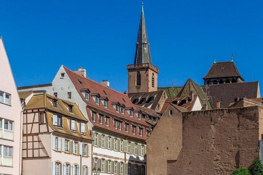 A historic town with traditional buildings, a prominent church tower, and a fortified wall. 4