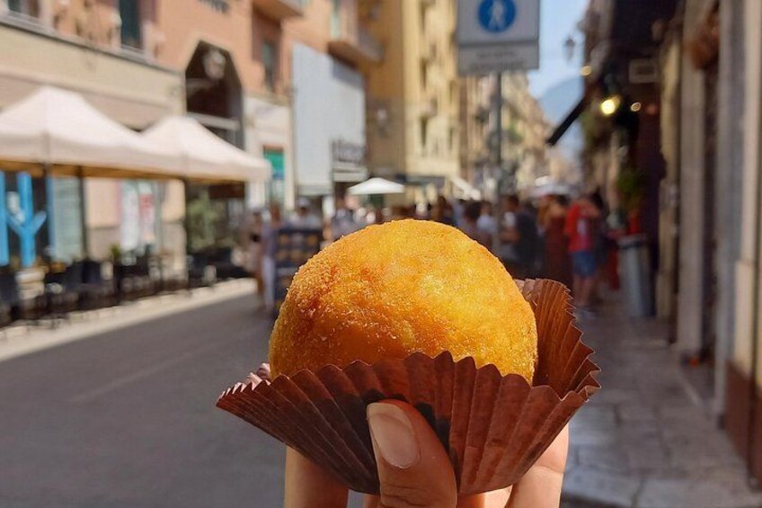 A person holding a round, golden-brown pastry in a brown paper cup. 4