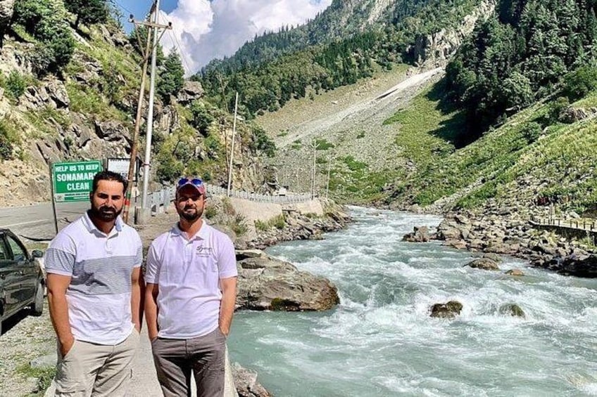 Dos hombres de pie junto a un río, con un cartel que dice 'HELP TO KEEP SOMARAN CLEAN'. 3