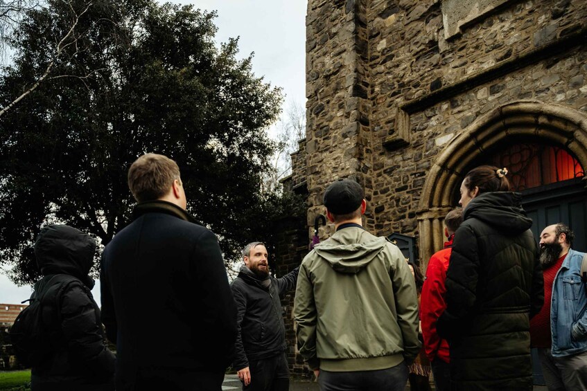 A group of people standing in front of a stone building with a large arched doorway. 2