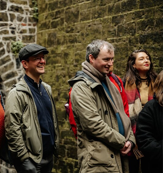 Three people standing in front of a stone wall. 5