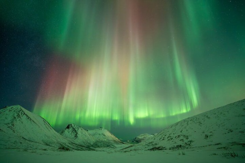 A snowy landscape with mountains and the Northern Lights. 4