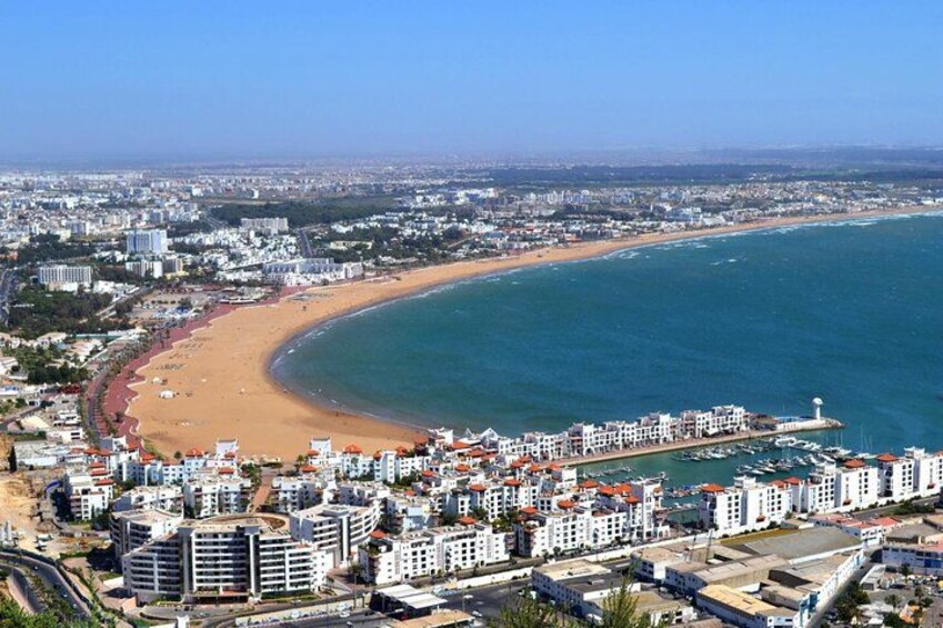 Eine Küstenstadt mit einer gewundenen Strandlinie, Wohnhäusern und blauem Himmel. 3