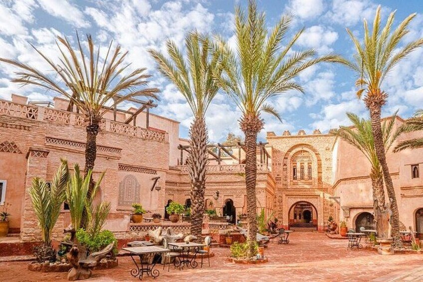 A courtyard with palm trees, a building with arches, and a tiled floor. 2