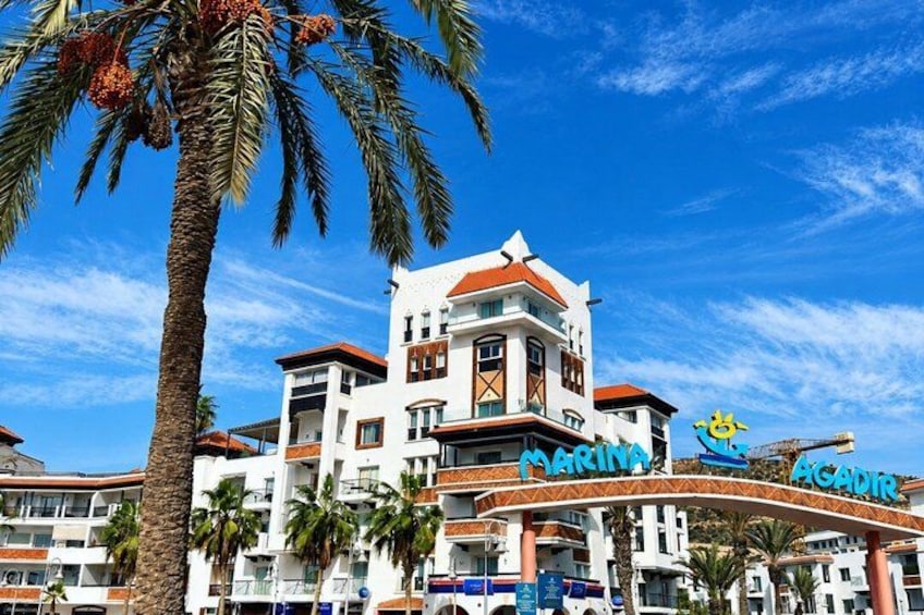 Un hotel de varios pisos con un letrero llamativo que dice 'MARINA ACATUR' y palmeras en primer plano. 5