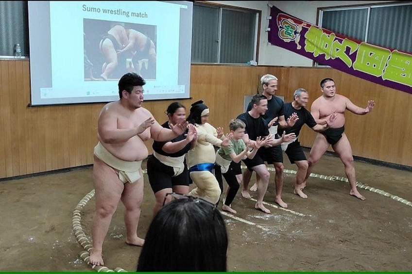 Un combate de sumo en curso, con participantes y público. 2