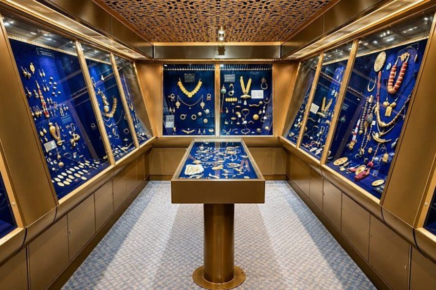 An interior with display cases of jewelry, a central table, and a patterned floor. 2