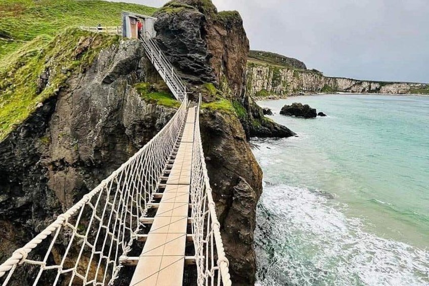 Un puente colgante sobre una costa rocosa con una caseta de vigilancia al final. 1