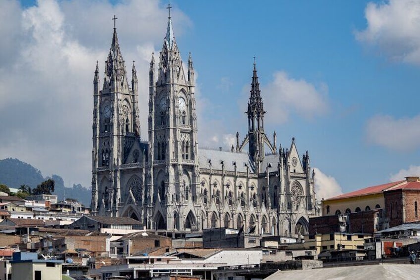 A Gothic cathedral with twin towers and a spire, surrounded by urban buildings. 1