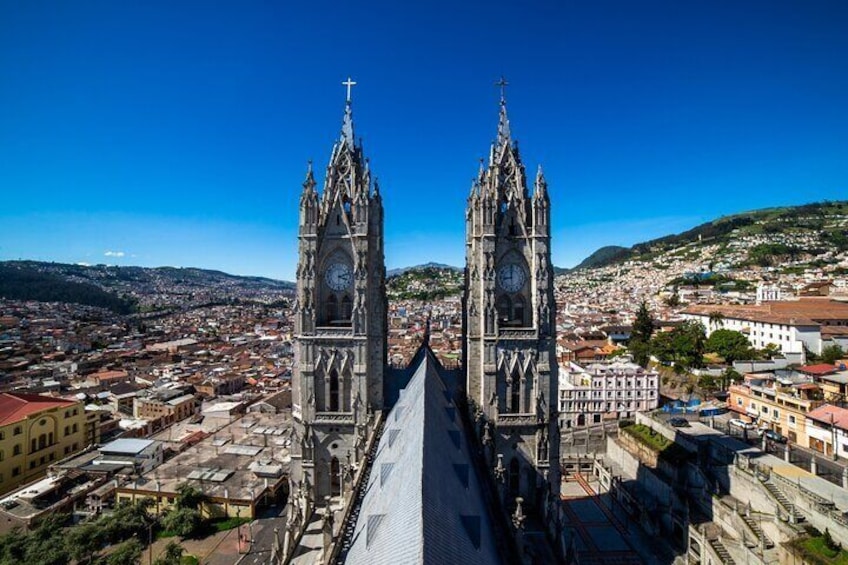 A cathedral with two tall towers and a clock, surrounded by a cityscape and hills. 3