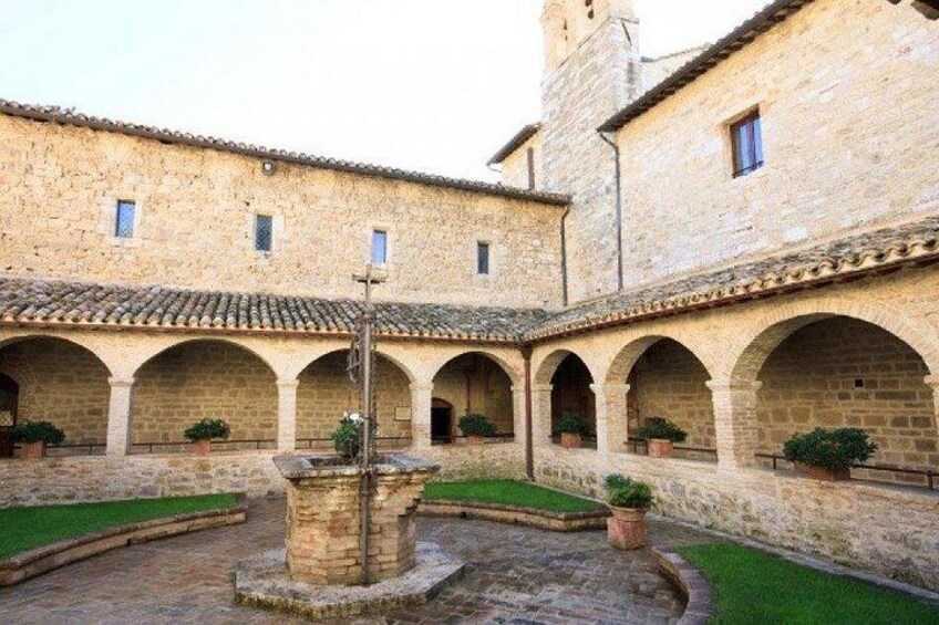 A courtyard with stone buildings, arched walkways, and a central fountain. 2