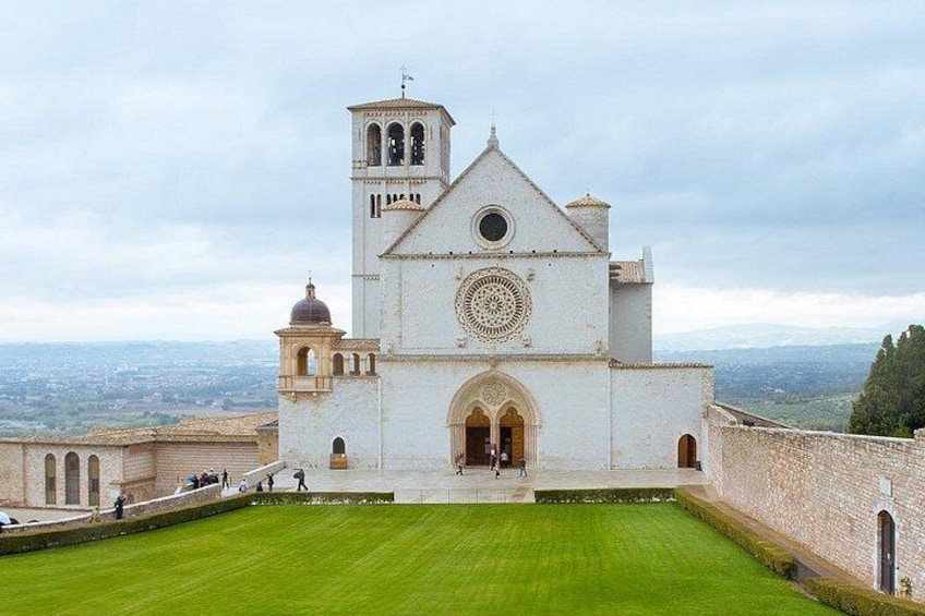 A white church with a bell tower, a circular window, and a grassy courtyard. 3