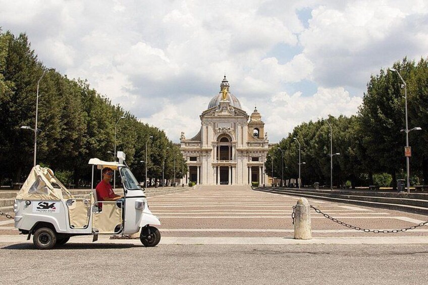 Un carrito de golf blanco con un conductor, estacionado en una carretera con un edificio grande y ornamentado al fondo. 2