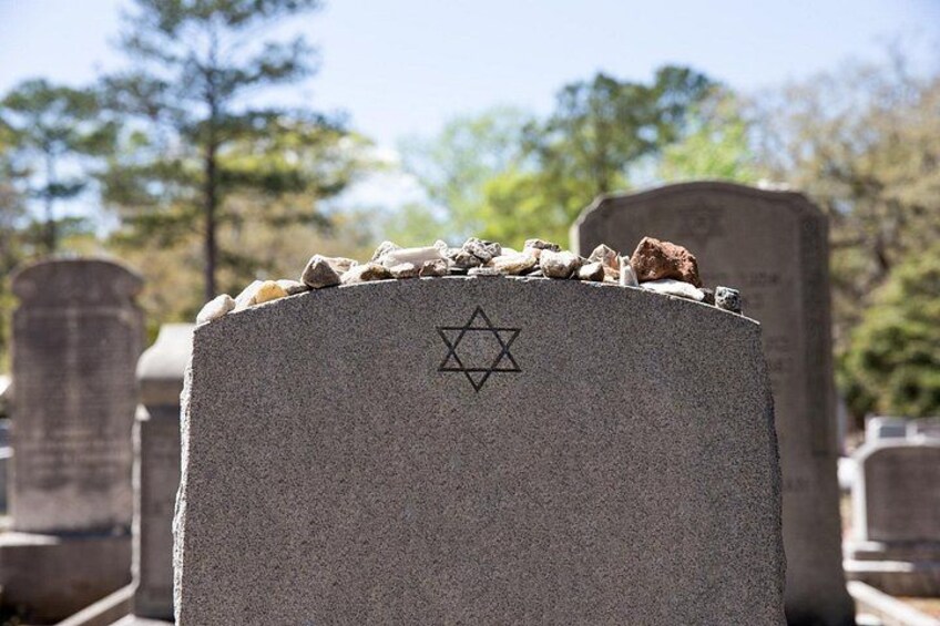 A gravestone with a Star of David symbol, surrounded by other gravestones in a cemetery. 2