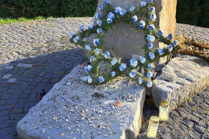 A stone monument with a floral wreath and candles. 1