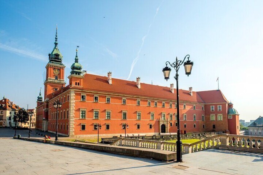 En stor byggnad i rött tegel med ett klocktorn och gröna kupoler. 3