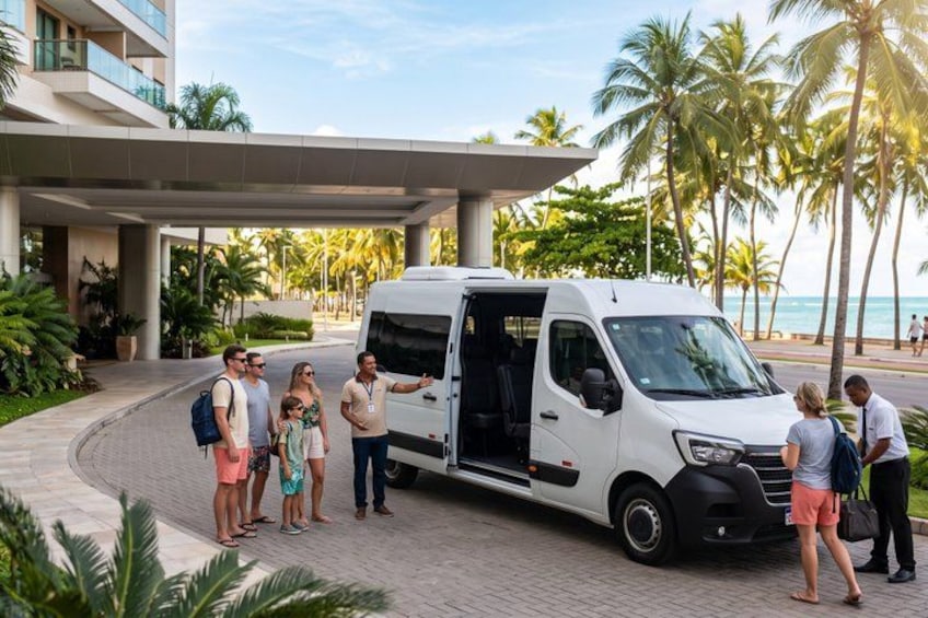 A white van parked in front of a building with palm trees and a beach in the background. 3