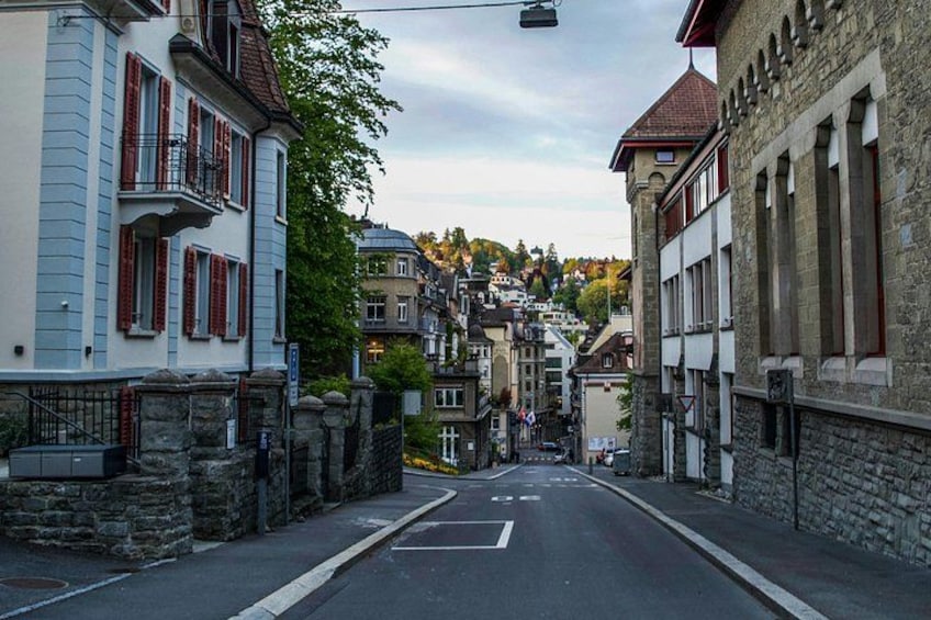 A narrow street flanked by historic buildings with stone facades and red shutters. 5