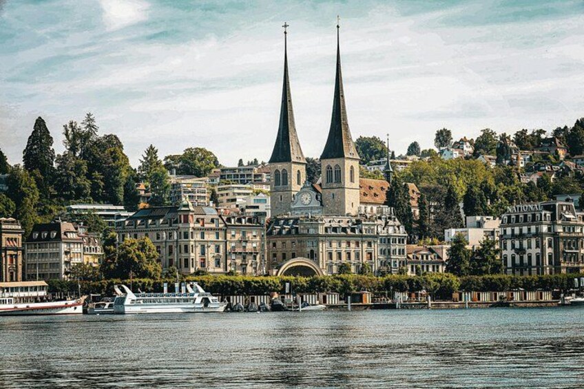 A cityscape with two prominent church spires, a river, and a boat. 4