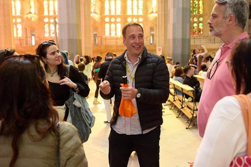 A person holding a drink in a crowded indoor setting with large windows and benches. 3