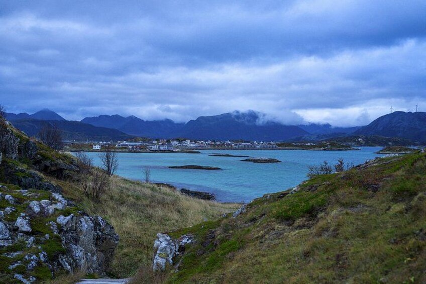 Een kustlandschap met bergen, een waterlichaam en een kleine nederzetting. 2