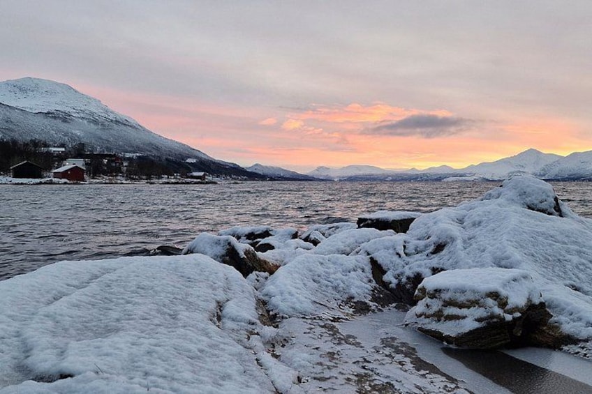 Un paysage enneigé avec une étendue d’eau, des rochers recouverts de neige et des montagnes en arrière-plan. 2