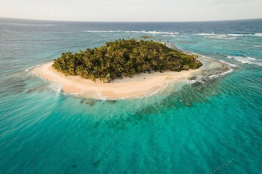 An aerial view of a small island with dense vegetation and clear turquoise waters. 3