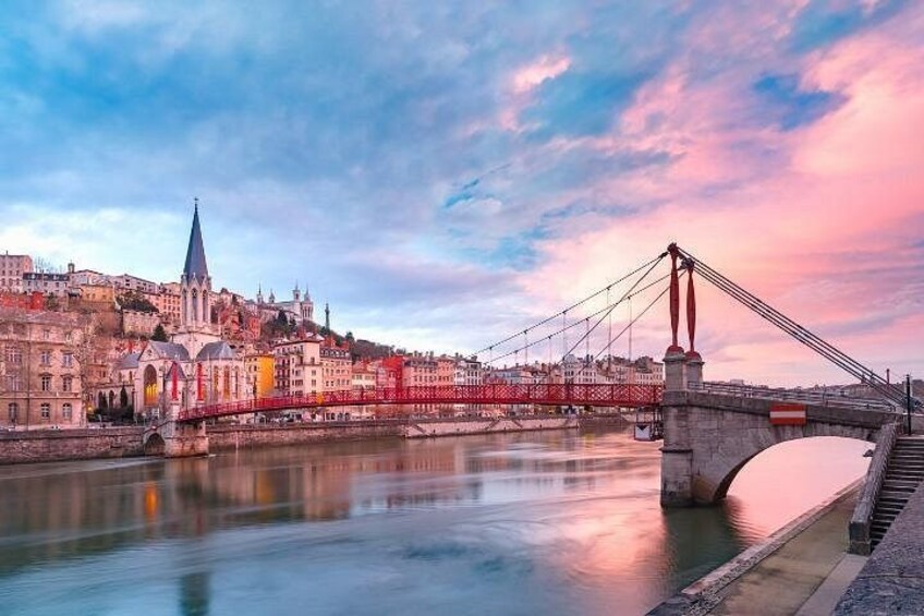 Eine Brücke über einem Fluss, eine Stadtansicht mit historischen Gebäuden und eine Kirche mit einem hohen Turm. 2