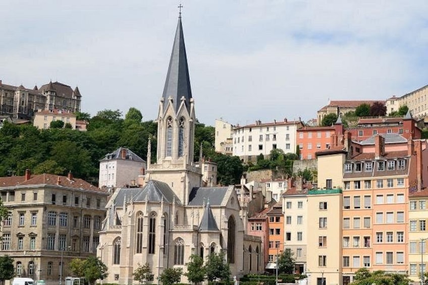 Eine historische Kirche mit einem hohen Kirchturm, umgeben von Wohnhäusern und üppigem Grün. 4