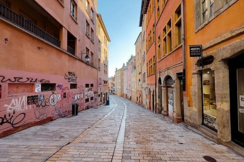 Eine enge Straße, gesäumt von Gebäuden, von denen einige mit Graffiti versehen sind. 3