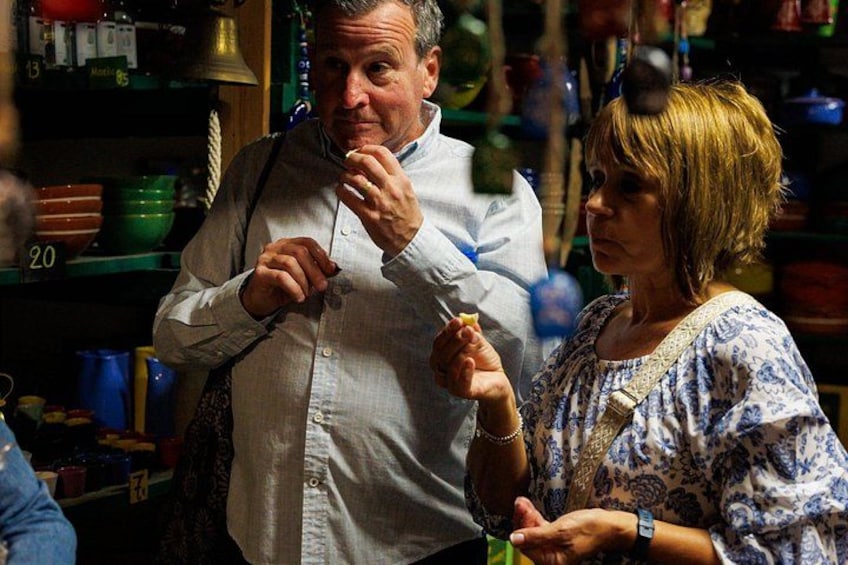 Una persona sosteniendo un objeto pequeño, posiblemente comida, en una tienda con estantes llenos de productos. 4