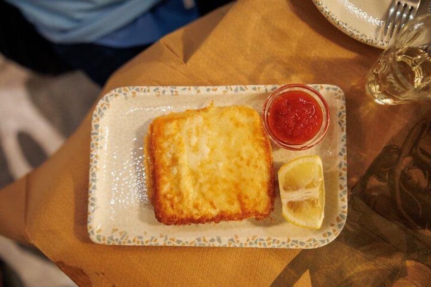 Un plato con un trozo de comida empanizada, una cuña de limón y un recipiente pequeño con salsa. 4