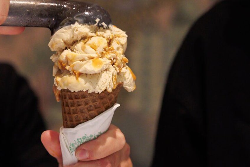 Una mano sosteniendo un cono de helado con cono de gofre y un envoltorio de papel. 3