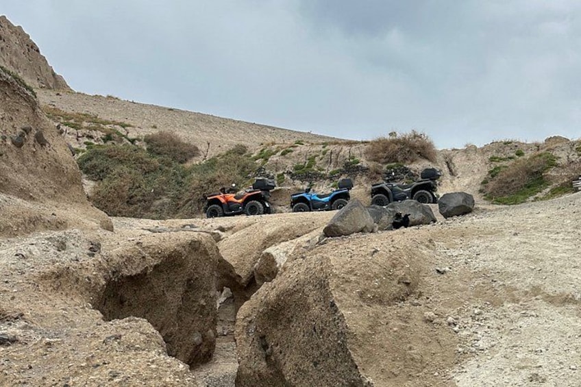 Des véhicules tout-terrain se frayent un chemin sur un terrain accidenté, parsemé de gros rochers et d’une végétation clairsemée. 4