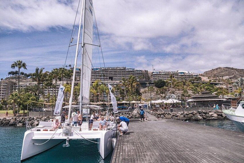 A sailboat docked at a pier with a cityscape in the background. 2