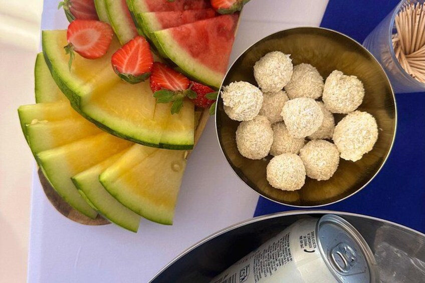 A fruit platter with watermelon, strawberries, and melon slices, and a bowl of coconut balls. 4